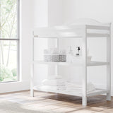 graco story white changing table with changing essentials on both shelves in nursery