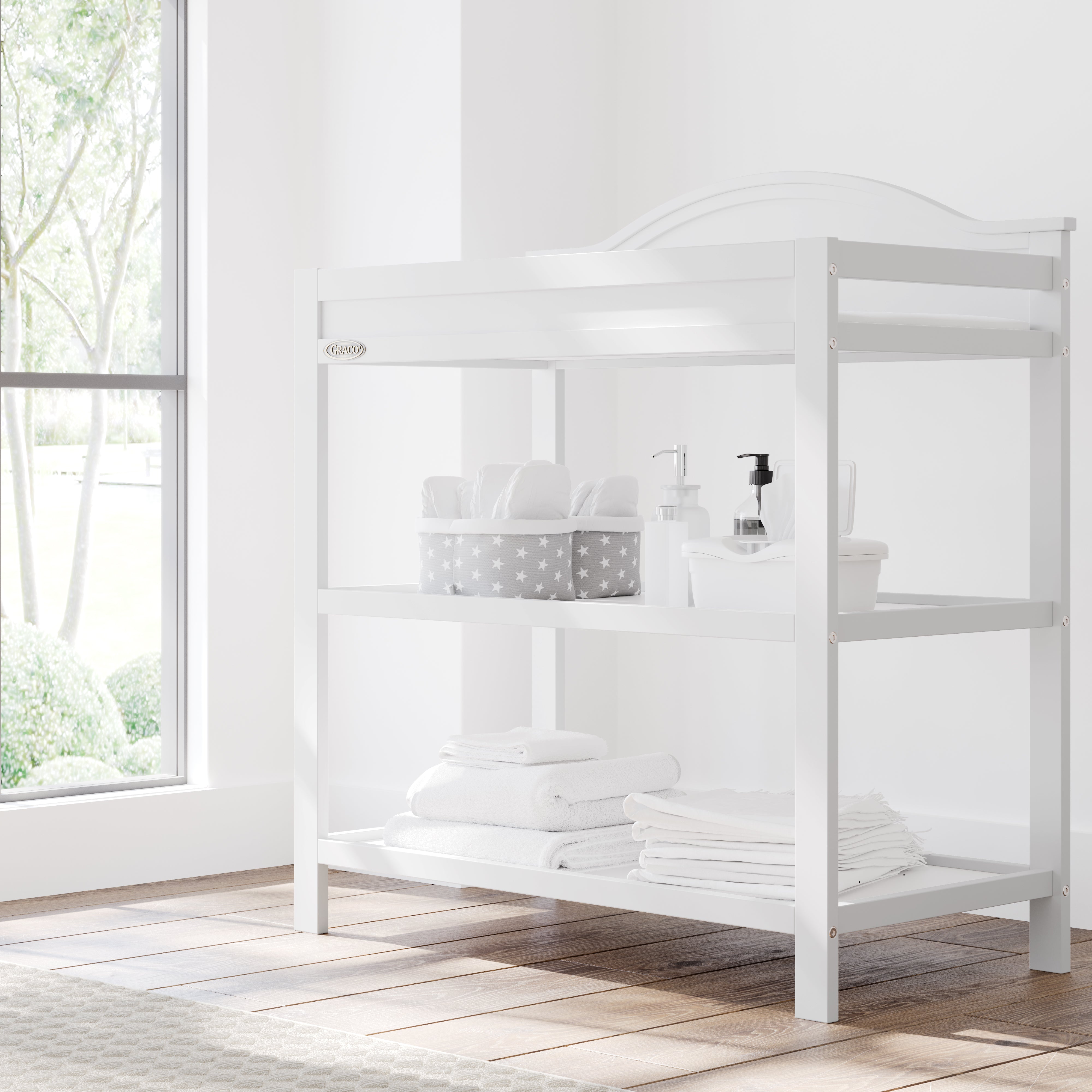 graco story white changing table with changing essentials on both shelves in nursery