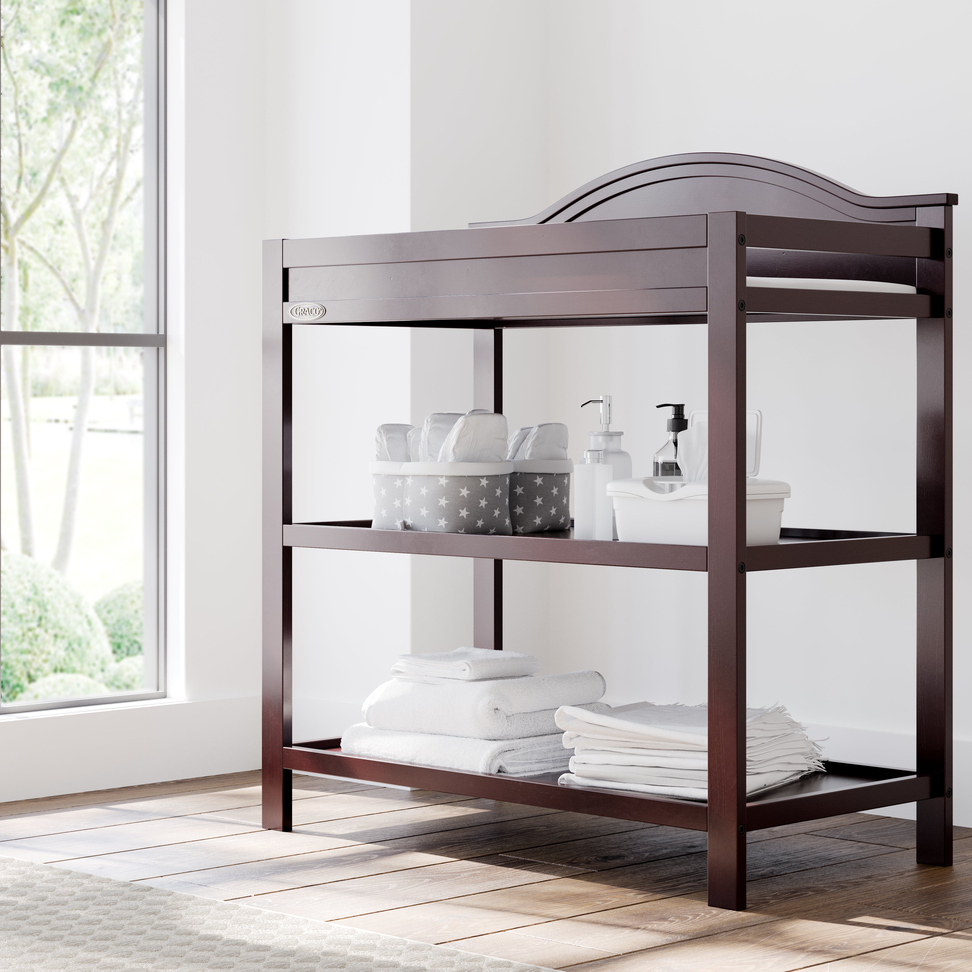 graco story espresso changing table with changing essentials on both shelves in nursery