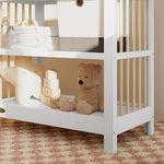 Close-up view of a white with driftwood changing table in the left corner.