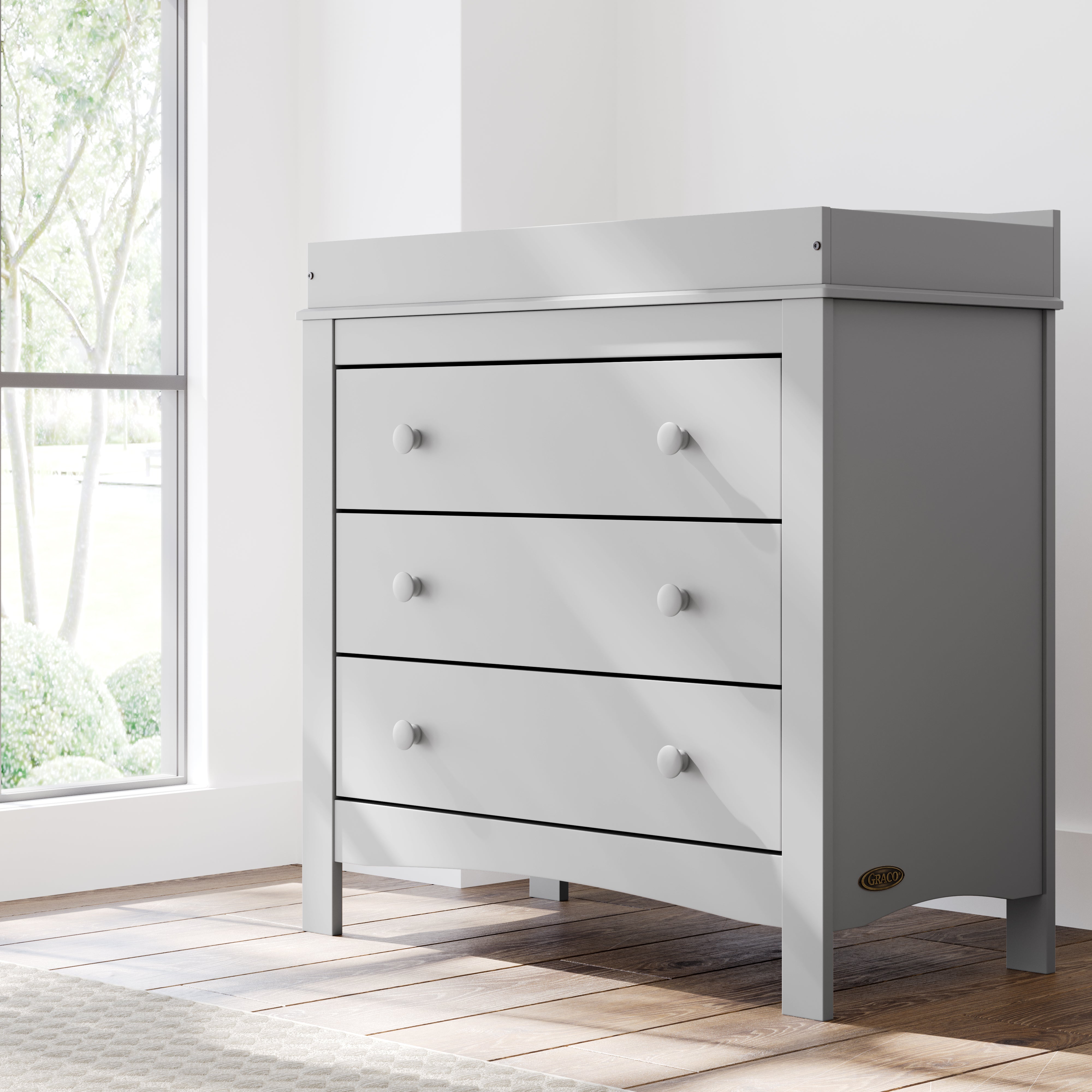 noah 3 drawer chest with topper in pebble gray finish in nursery by window