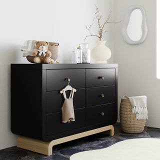 Angled view of black 6 drawer dresser with driftwood base in nursery