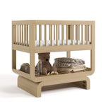 Santorini driftwood bassinet angle view with baby items on bottom