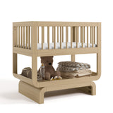 Santorini driftwood bassinet angle view with baby items on bottom