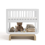 Santorini white with driftwood bassinet front view with baby items on bottom