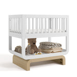 Santorini white with driftwood bassinet angle view with baby items on bottom