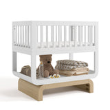Santorini white with driftwood bassinet angle view with baby items on bottom