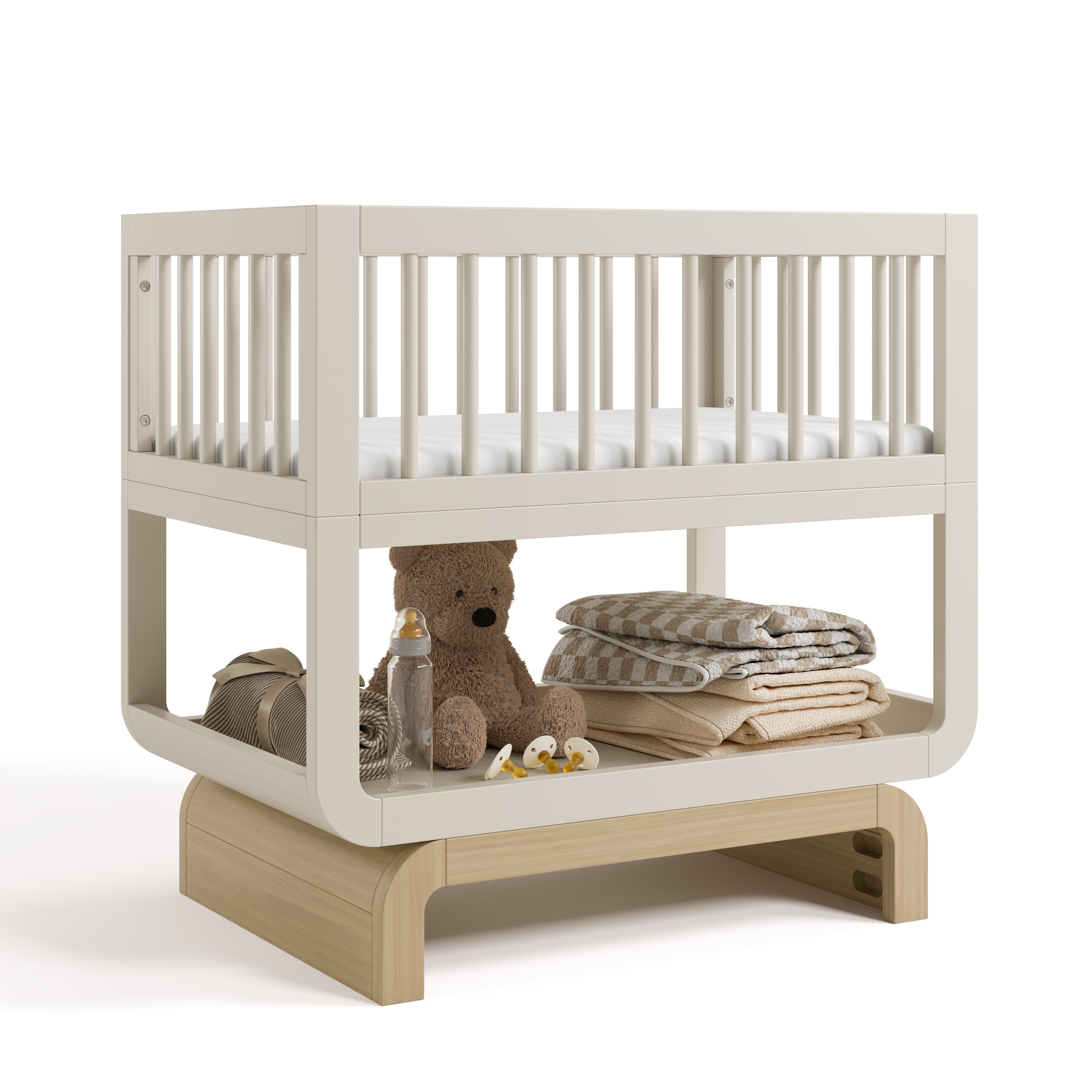 Santorini frosted oat with driftwood bassinet angle view with baby items on bottom