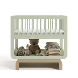 Santorini sage with driftwood bassinet front view with baby items on bottom