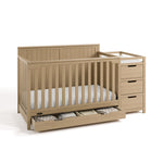 Hadley driftwood crib and changer with drawer open and baby items inside angle view