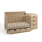 Hadley driftwood crib and changer with drawer open and baby items inside angle view