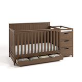 Hadley hazelnut crib and changer with drawer open and baby items inside angle view