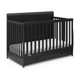 Angled view of black crib with drawer
