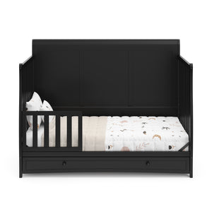 Black crib with drawer in toddler bed conversion with one safety guardrail