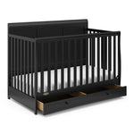 Angled view of black crib with open drawer