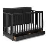 Angled view of black crib with open drawer