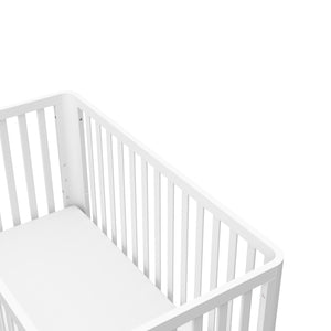 top view of a white crib with a natural wood color base