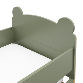 close up view of a olive-colored toddler bed