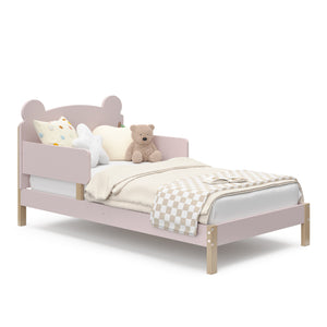 Side view of a blush-colored toddler bed