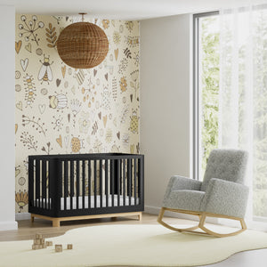 Rocker chair with natural wood base and salt-and-pepper boucle fabric, accompanied by a black crib with a natural base in a nursery setting