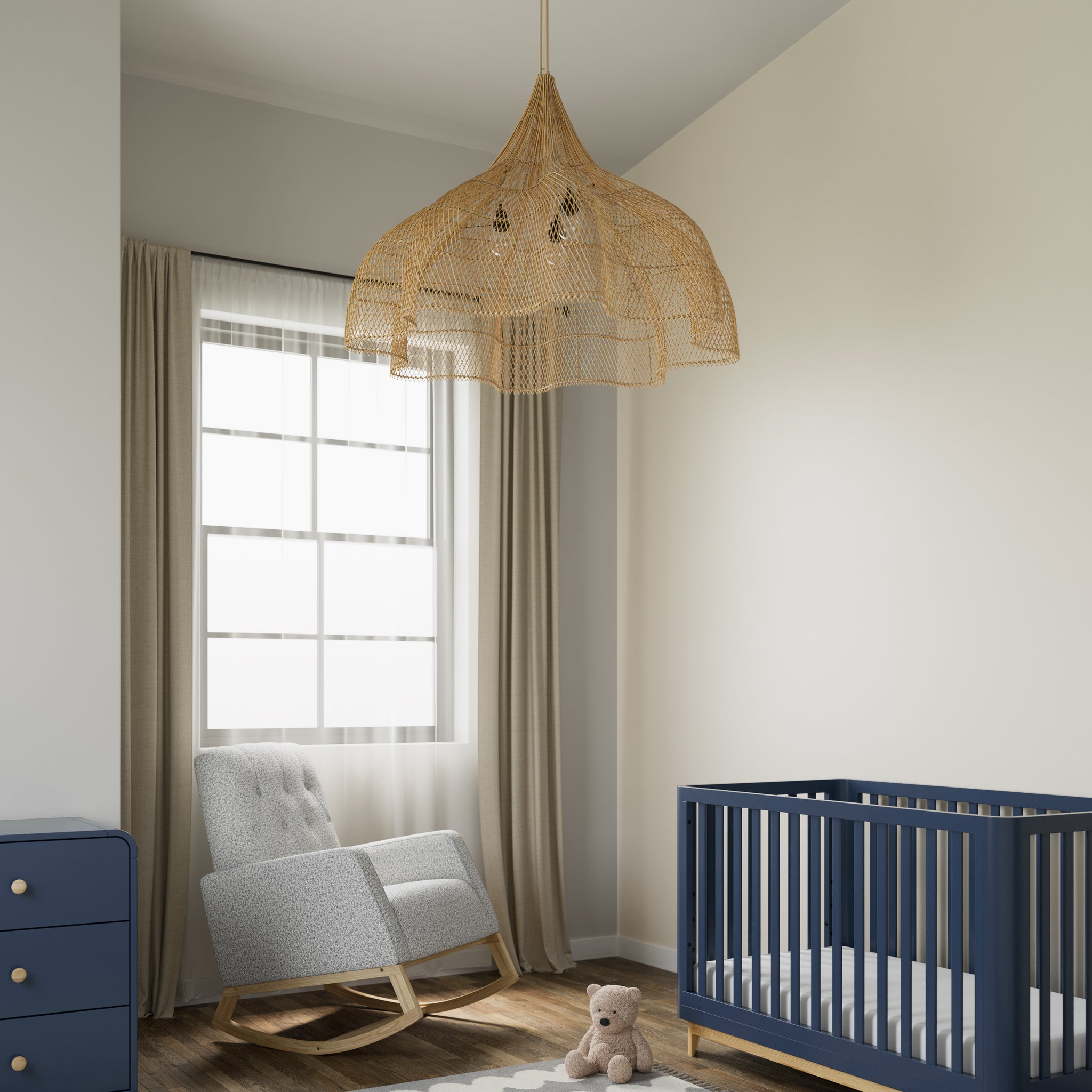 Rocker chair with natural wood base and salt-and-pepper boucle fabric, accompanied by a blue crib with a natural base and a matching blue dresser featuring driftwood knobs, all in a nursery setting.