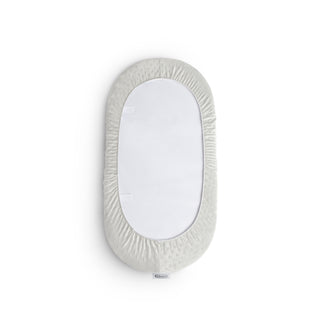 Back view of an oval changing pad with a textured cover and showing non-skid bottom surface