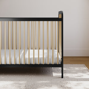 Two-tone black and natural wood baby crib on beige rug