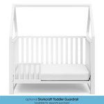 White crib in toddler bed conversion with one safety guardrail graphic