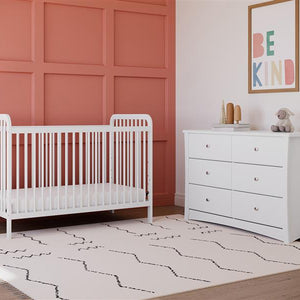 white crib in nursery with 6 drawer chest