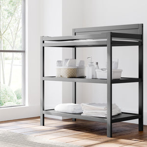 Angled view of gray changing table with storage in nursery 
