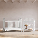 Olivia white changing table next to crib in a nursery