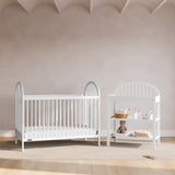 Olivia white changing table next to crib in a nursery