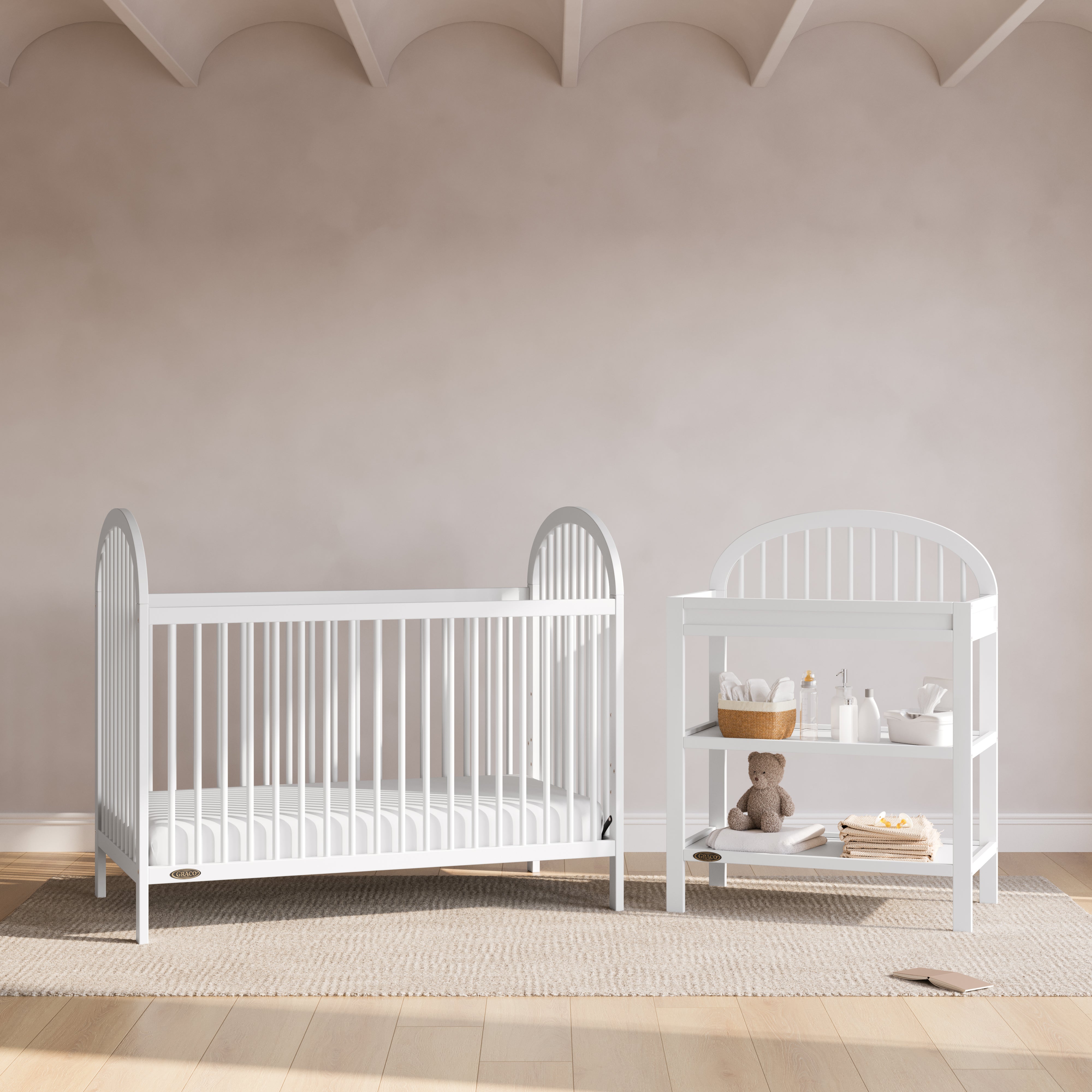 Olivia white changing table next to crib in a nursery