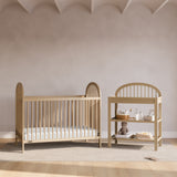 Olivia driftwood changing table next to crib in a nursery