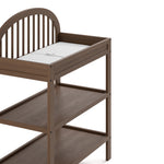 Olivia hazelnut changing table close up of changing topper, shelves, and headboard