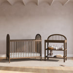 Olivia hazelnut changing table next to crib in a nursery