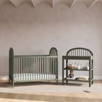 Olivia olive changing table next to crib in a nursery