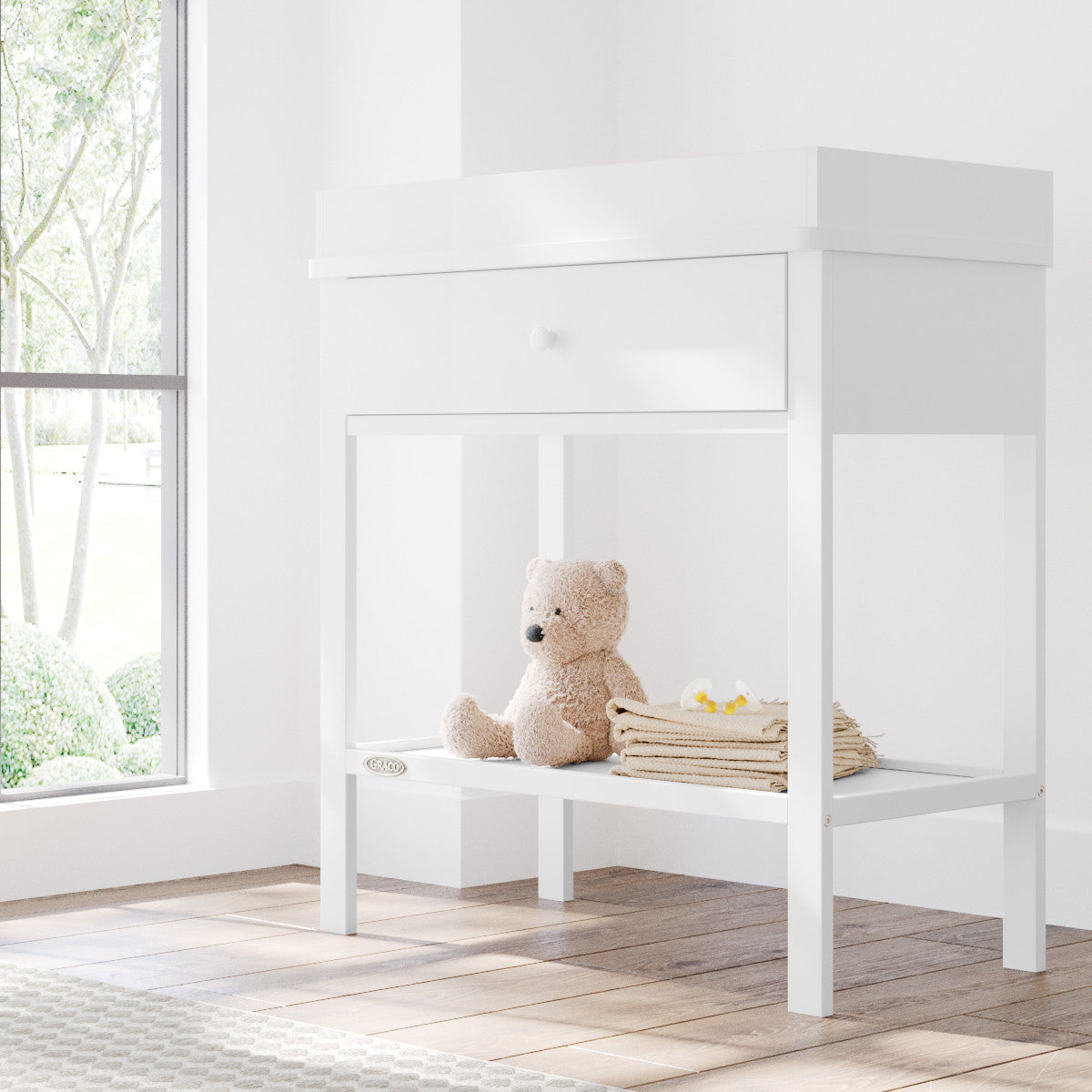 White Graco storage changing table in a nursery