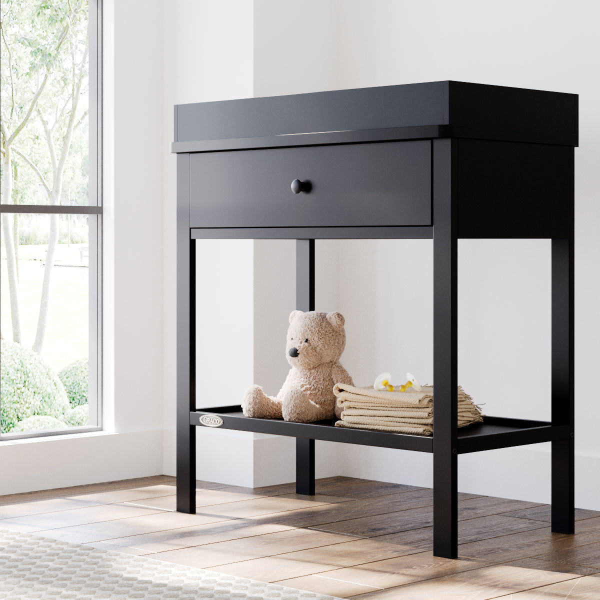 Black Graco storage changing table in a nursery