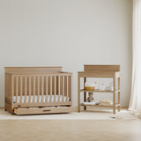 Tristan driftwood crib with drawer next to changing table in a nursery