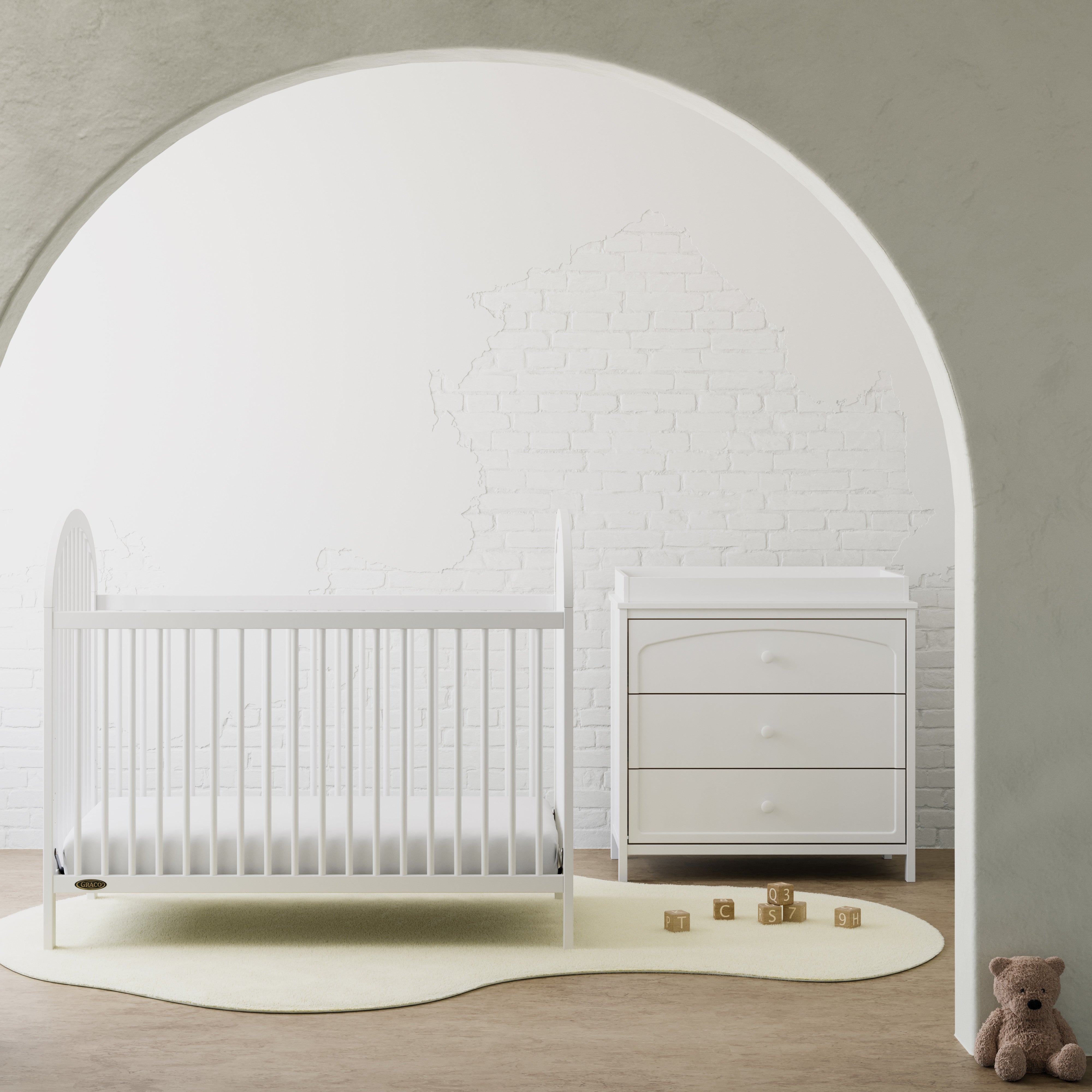 Olivia white 3 drawer chest with changing topper next to crib in a nursery
