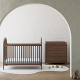 Olivia hazelnut 3 drawer chest with changing topper in a nursery beside crib