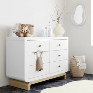 Angled view of white 6 drawer dresser with driftwood base in nursery
