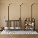 Olivia hazelnut crib in a nursery next to changing table