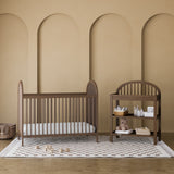Olivia hazelnut crib in a nursery next to changing table