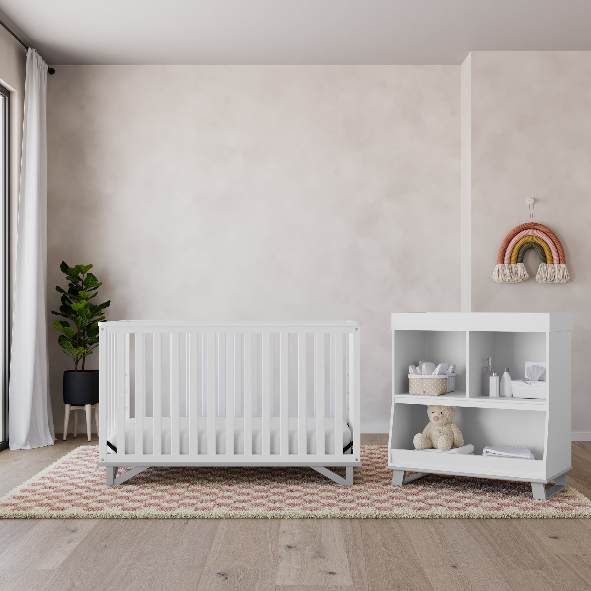 Front view of white crib with pebble gray in nursery with changing table