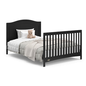 Black crib in full-size bed with headboard and footboard conversion