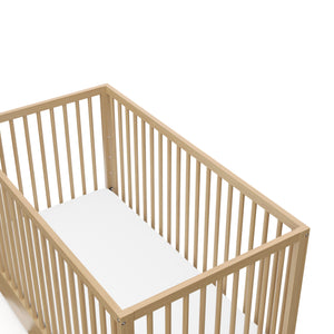 Close-up view of white crib with drawer