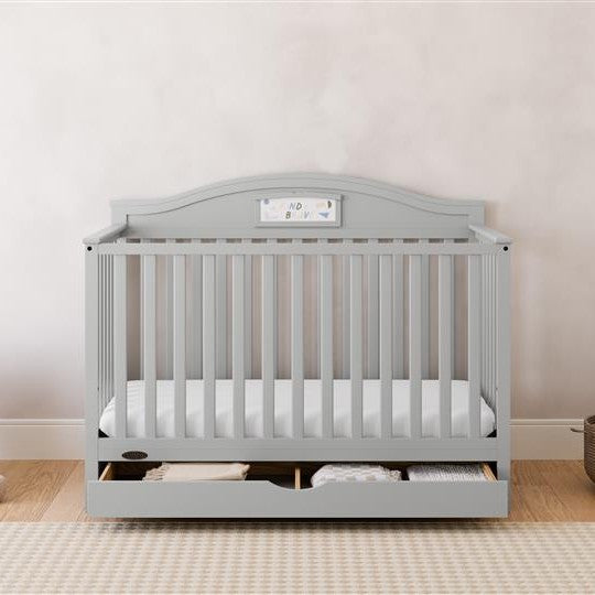 Story pebble gray crib with drawer in a nursery