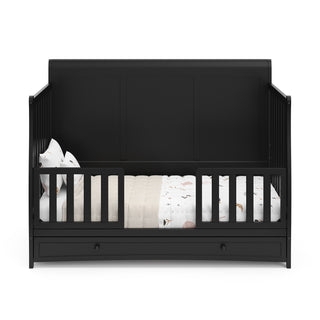 Black crib with drawer in toddler bed conversion with two safety guardrails